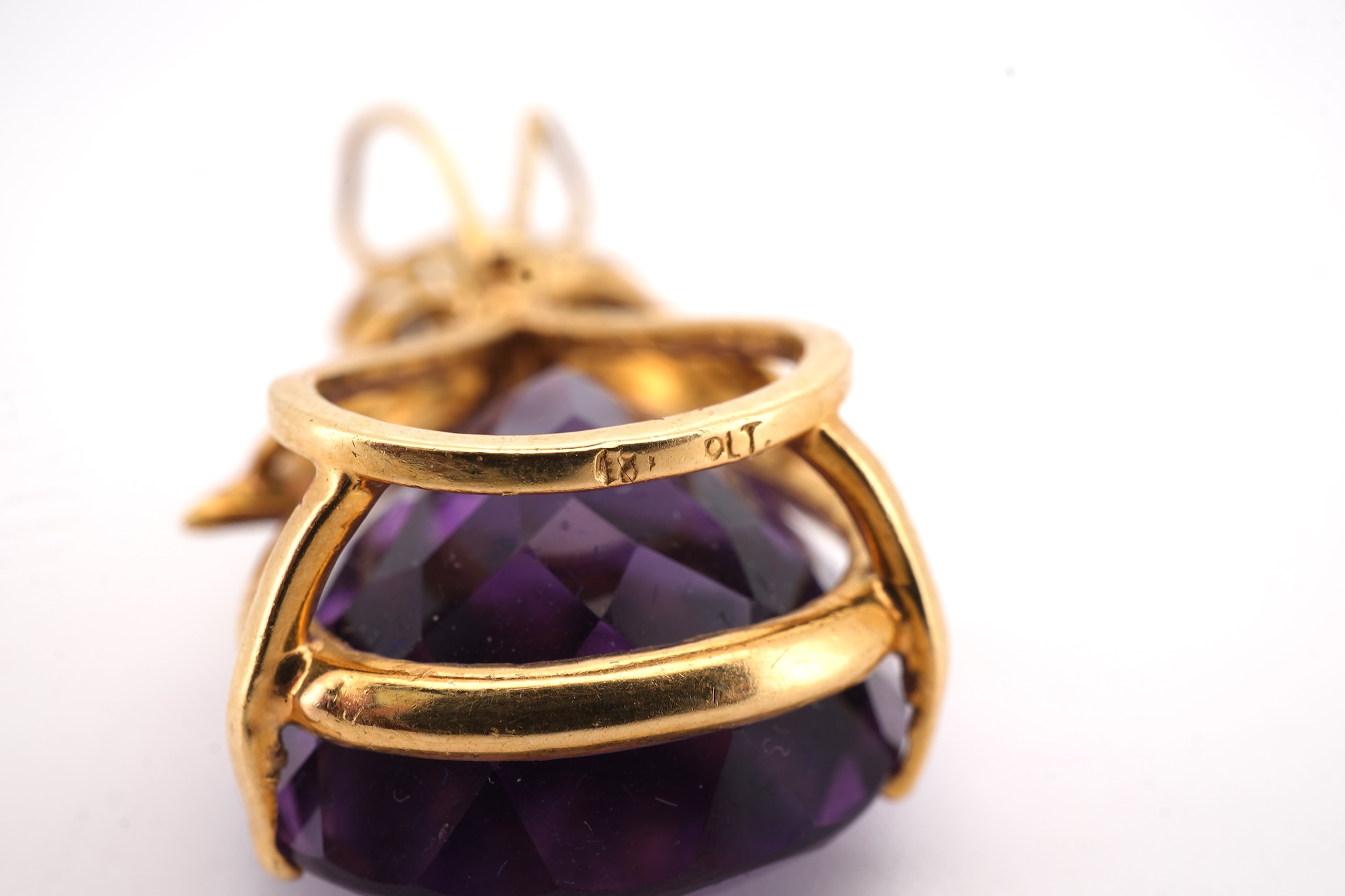 An Amethyst and diamond pendant, claw-set with a pear-shaped amethyst, topped with a foliate surmount in textured gold, accented with and arc of brilliant-cut diamonds totalling approximately 0.30 carats, length 3.5cm, s